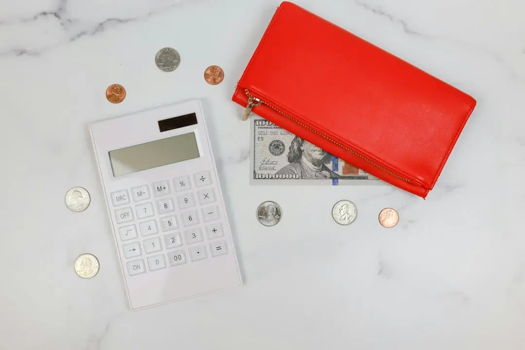 A white calculator, US coins, a dollar bill and a red wallet on a marble table, for working out what a Flixaria plan costs per month